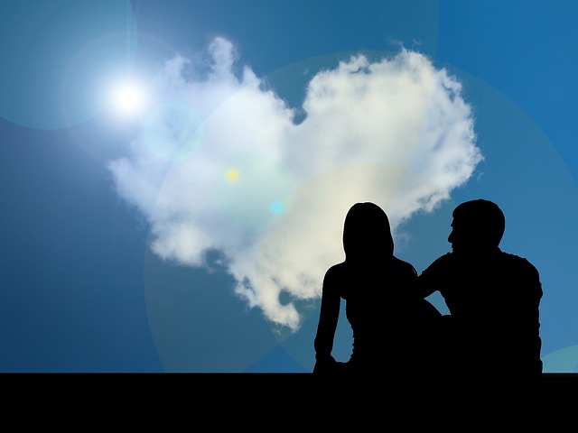 ハートの形の雲を見るカップルのシルエット